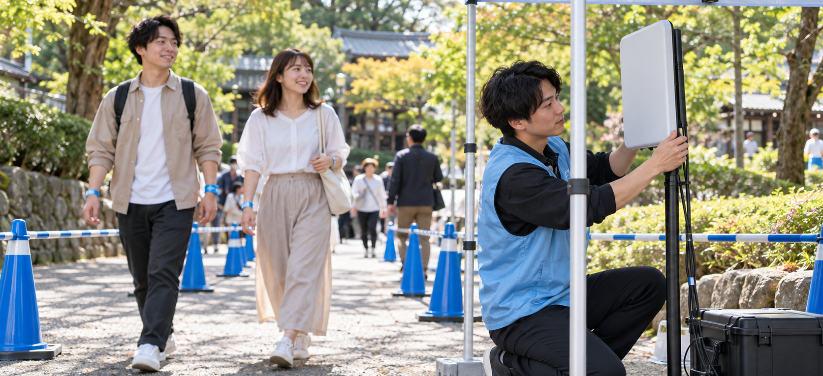 屋外イベントの受付で、スタッフが参加者の手首に使い捨てのRFIDリストバンドを装着するイメージ